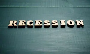 Drewniane litery układają napis "RECESSION". To słowo często pojawia się, gdy zastanawiamy się, co to znaczy recesja i jak wpływa na gospodarkę.