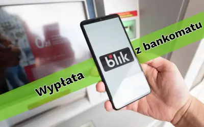 Dłoń trzyma smartfon z logo Blik przed bankomatem. Można w ten sposób wypłacić pieniądze.